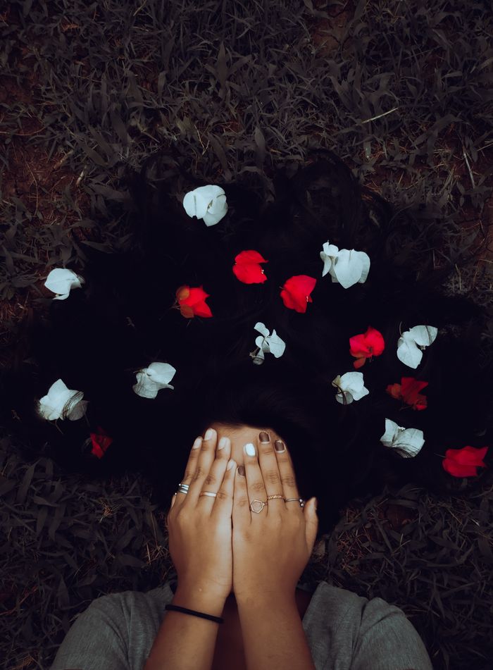 Captivating portrait with red and white flowers arranged in dark hair, evoking a natural, creative atmosphere.
