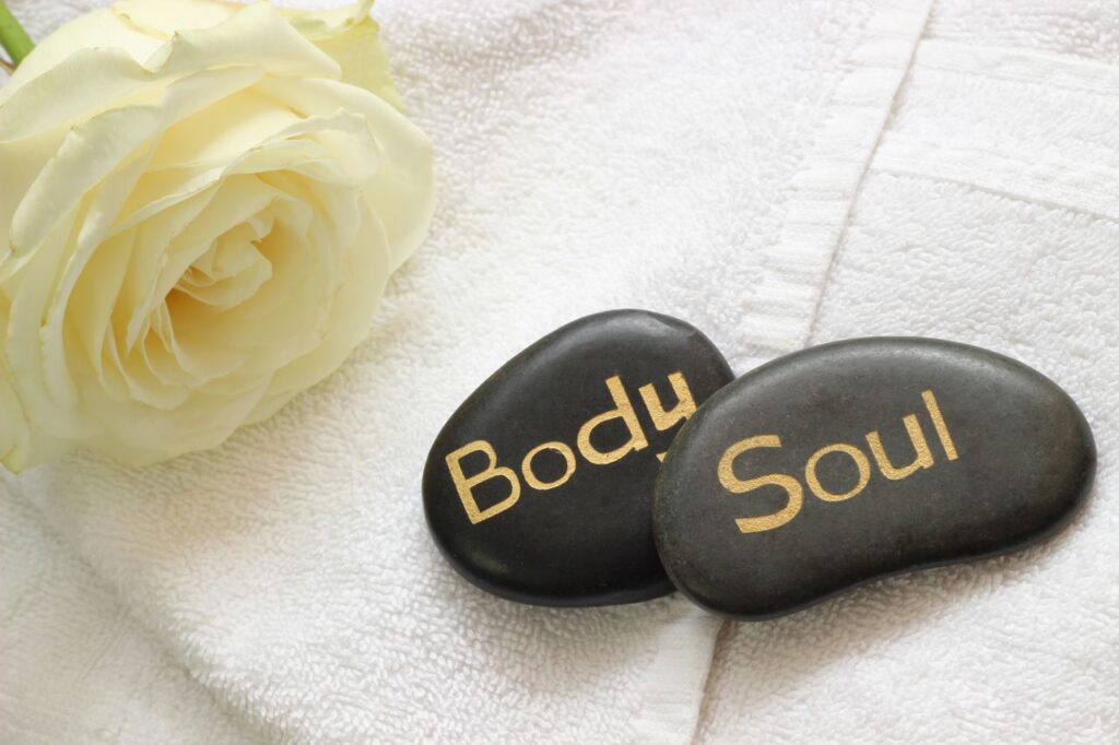 Tranquil spa arrangement featuring a white rose and engraved stones on a towel for relaxation.